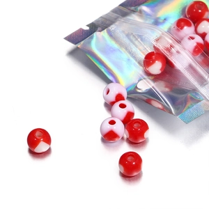 Detailed view of red and white mushroom beads spilling from a holographic pouch