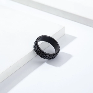 Macro detail of men's matte black stainless steel spinner ring with brick texture