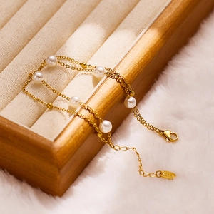 Bracelet double couche en acier doré avec perles et billes sur plateau à bijoux en bois