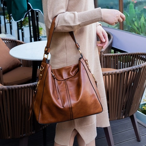 Outdoor shot of brown litchi leather tote bag with tassel detail and gold hardware