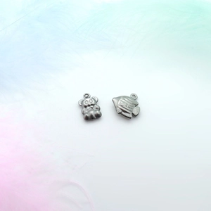 Detail of silver bear and fish hollow pendants on soft feathers for jewelry making