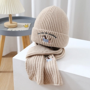 Detail of beige ribbed knit hat and scarf set featuring cartoon dog embroidery and soft texture