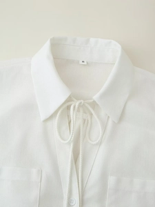 Detailed macro view of white linen blouse neckline with rope drawstrings and collar