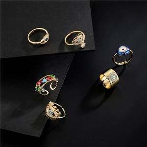 18K gold plated evil eye rings set with colorful zircons on a dark geometric background