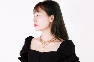 Détail d'un collier doré multicouche avec perle baroque et pendentif pièce sur mannequin