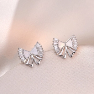 Detail of silver bow earrings with zircon stones and mother-of-pearl on silk