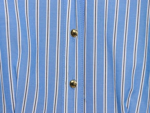 Detailaufnahme des blau-weiß gestreiften Stoffes mit polierten goldenen Metallknöpfen