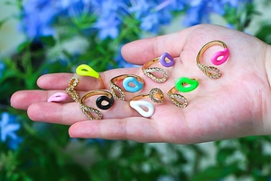 Close-up of gold open rings with colorful enamel teardrops and micro-pave crystals