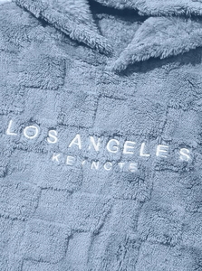 Macro shot of light blue sherpa hoodie featuring Los Angeles Keynote embroidery and grid texture