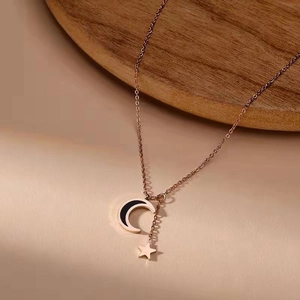 Rose gold necklace with moon and star pendant on an elegant wooden tray display