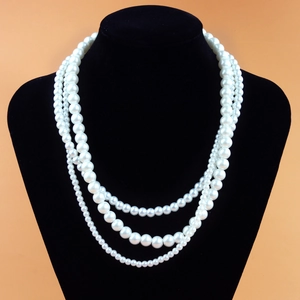 Three-layer elegant pearl necklace with white faux pearls on a black velvet neck mannequin