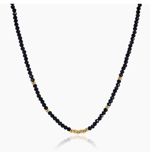 Close-up of beaded necklace featuring faceted black rhinestones and gold accent beads
