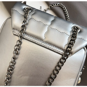Detail shot of silver quilted faux leather texture with elegant metal chain strap