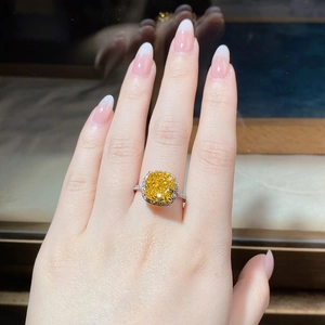 Detail of a cushion-cut yellow diamond halo ring in S925 silver worn on a finger