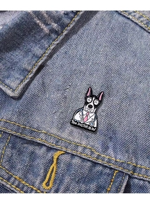 Detail of Boston Terrier doctor enamel pin with 'The DOGTOR is in' text on blue denim