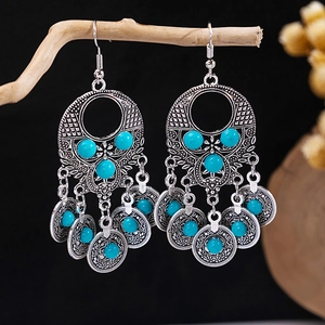 Detail of bohemian tassel earrings with turquoise beads hanging on a rustic branch