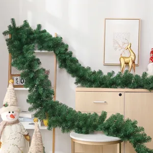 Lush green artificial Christmas flocked garland draped over stairs and wooden tables