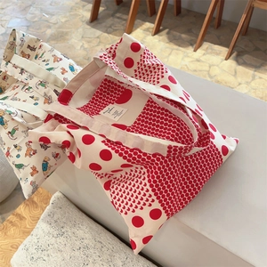 Detail of red polka dot and cartoon dog print canvas tote bags on a display stand