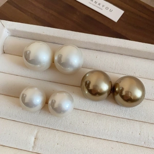 Détail de boucles d'oreilles perles blanches et champagne sur un plateau à bijoux
