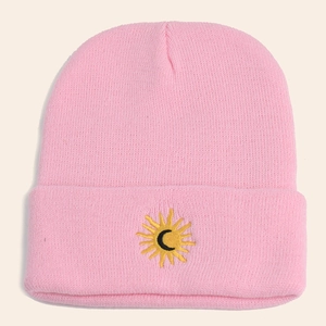 Detailed view of pink knitted beanie featuring sun and moon embroidery on folded brim