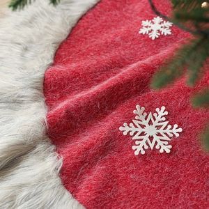 Red plush Christmas tree skirt with white snowflake patterns and grey faux fur trim