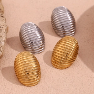 Macro shot showing textured striped texture on gold and silver oval stainless steel earrings