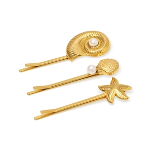 Détail de 3 épingles à cheveux dorées avec coquillages, étoiles de mer et perles sur blanc