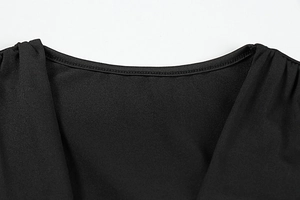 Detail of elegant black dress showing high-quality stitching and cross V-neckline texture