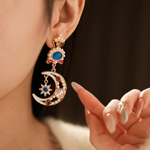 Macro shot of vintage gold earrings with asymmetric moon star design and colorful pearls