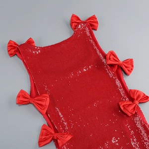 Close-up of red sequin party dress with decorative satin bows and shimmering texture