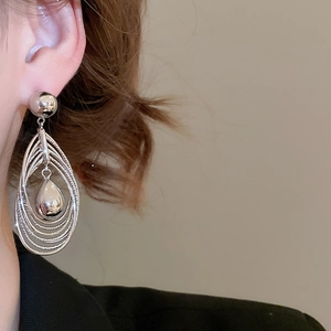 Side view of multi-layer concentric oval drop earrings in polished silver on a model
