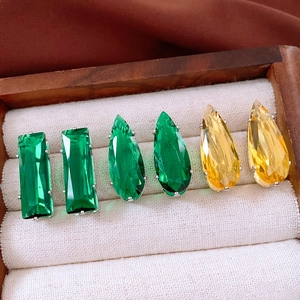 Detailed close-up of vintage square and teardrop zircon stud earrings in a wooden jewelry box
