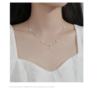 Close-up of S925 silver four-leaf clover necklace with sparkling cubic zirconia on a model