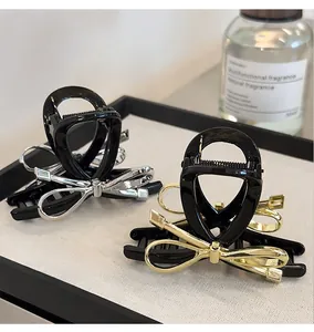 Detail view of black hair claw clips with gold and silver metallic bow accents