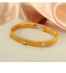 Detailed close-up of a gold-plated snake bone clover bracelet with crystal rhinestones