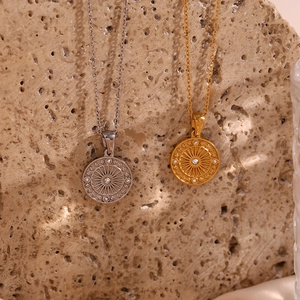 Detail of round compass pendants with sunburst texture and white zircon stones