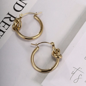 Detailed macro view of gold-tone knot earrings with a polished finish and latch back closure