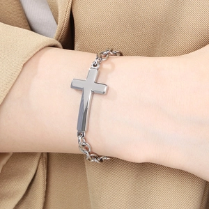 Detail of silver stainless steel cross bracelet on wrist with O-chain link design