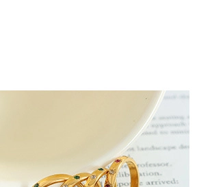 Close-up of gold multi-layer crossover ring with red, green, and white zircon stones