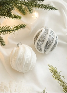 Nahaufnahme von glitzernden weißen und silbernen Weihnachtskugeln mit Samtstreifen