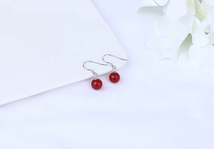 Detailed view of red agate bead earrings with S925 sterling silver hooks on white fabric