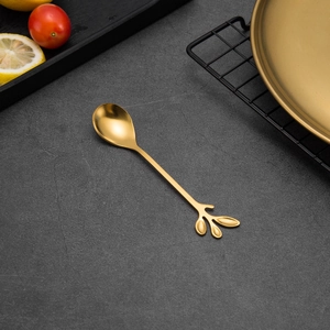 Close-up of golden leaf-shaped handle on creative stainless steel dessert spoon