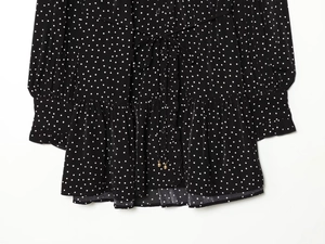 Detail of waist tie and double-layered ruffled hem on black and white polka dot dress