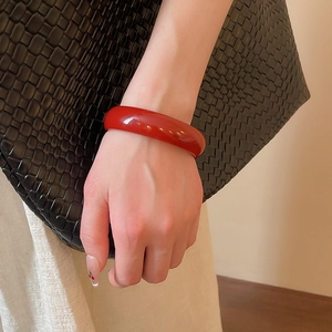 Close-up of a glossy red resin geometric bangle bracelet worn on a model's wrist