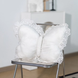 Detailed view of white butterfly pillow featuring intricate lace embroidery and soft plush texture