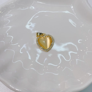 Detailed shot of golden heart-shaped pendant with amber cat-eye stone and pavé setting