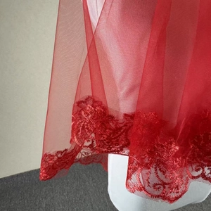 Close-up of vibrant red bridal veil featuring delicate floral lace embroidery detail