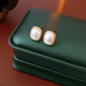 Macro detail of square pearl earrings in rose gold setting on a premium gift box