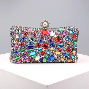 Close-up of vibrant multi-colored rhinestones and pearl clasp on luxury metal evening bag