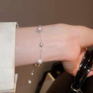 Detailed shot of irregular white pearls on a slim silver chain bracelet for women